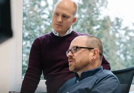 Zwei Kollegen im Büro diskutieren am Computer, Teamarbeit und Beratung